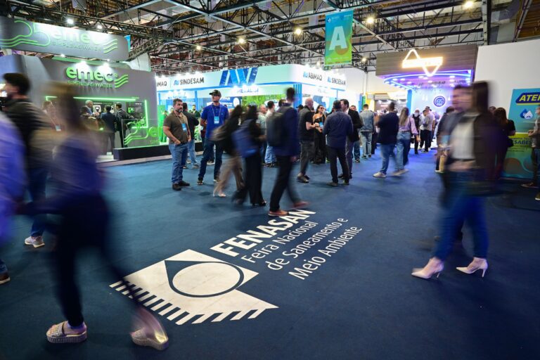 Movimento intenso de visitantes na Fenasan 2025, Feira Nacional de Saneamento e Meio Ambiente, com estandes de empresas do setor e profissionais circulando pelos corredores do evento.